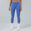 A person wearing royal blue high-waist yoga leggings and white socks standing against a light gray background.