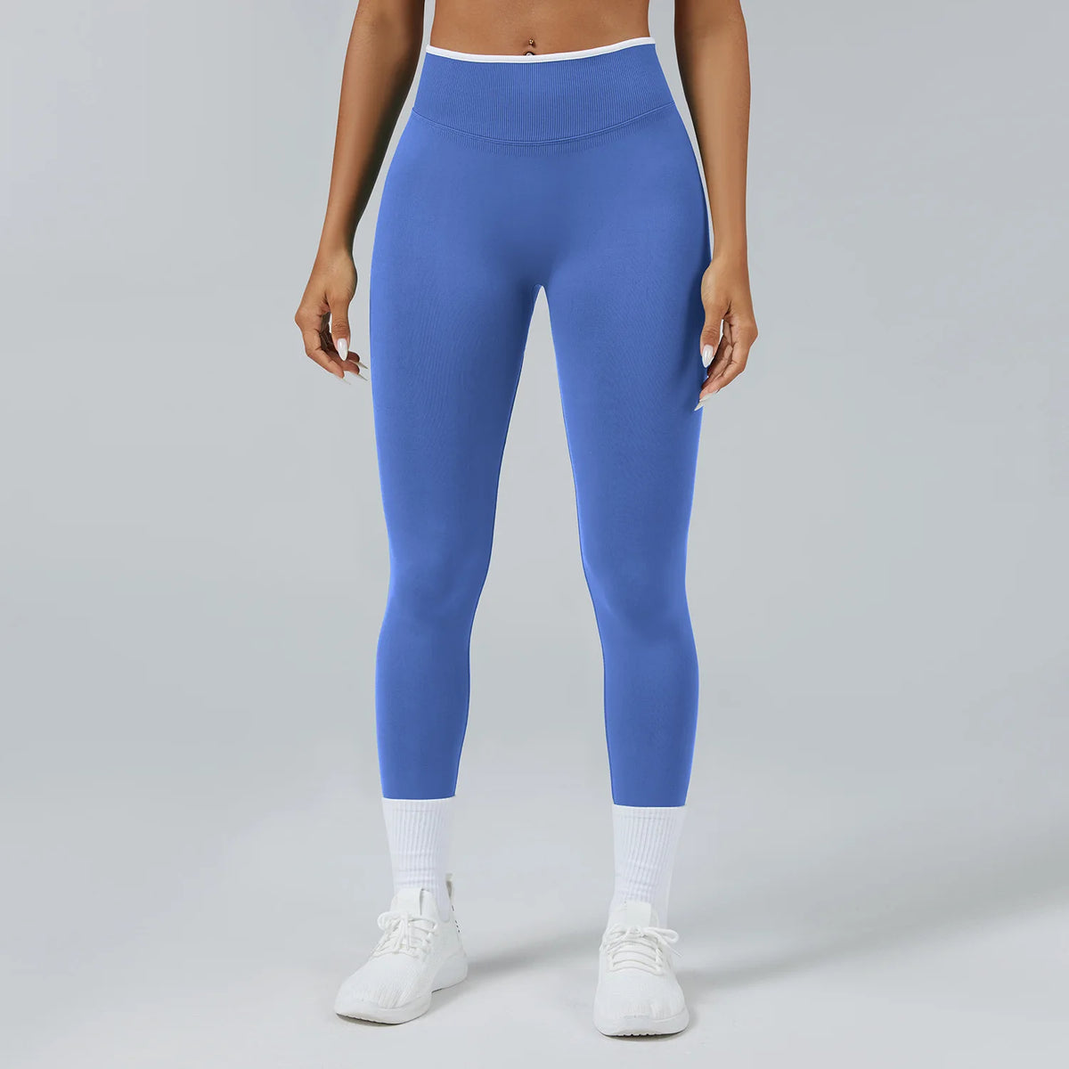 A person wearing royal blue high-waist yoga leggings and white socks standing against a light gray background.