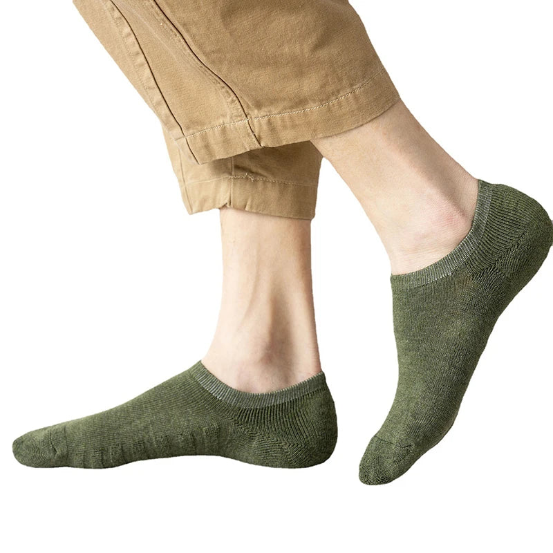 A close-up of a person wearing olive green cotton crew socks with tan pants.