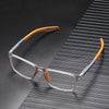 Clear-framed reading glasses with orange accents resting on a dark, striped surface.