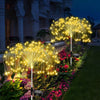 Luces de hadas doradas en una fuente iluminando un camino de jardín exterior por la noche