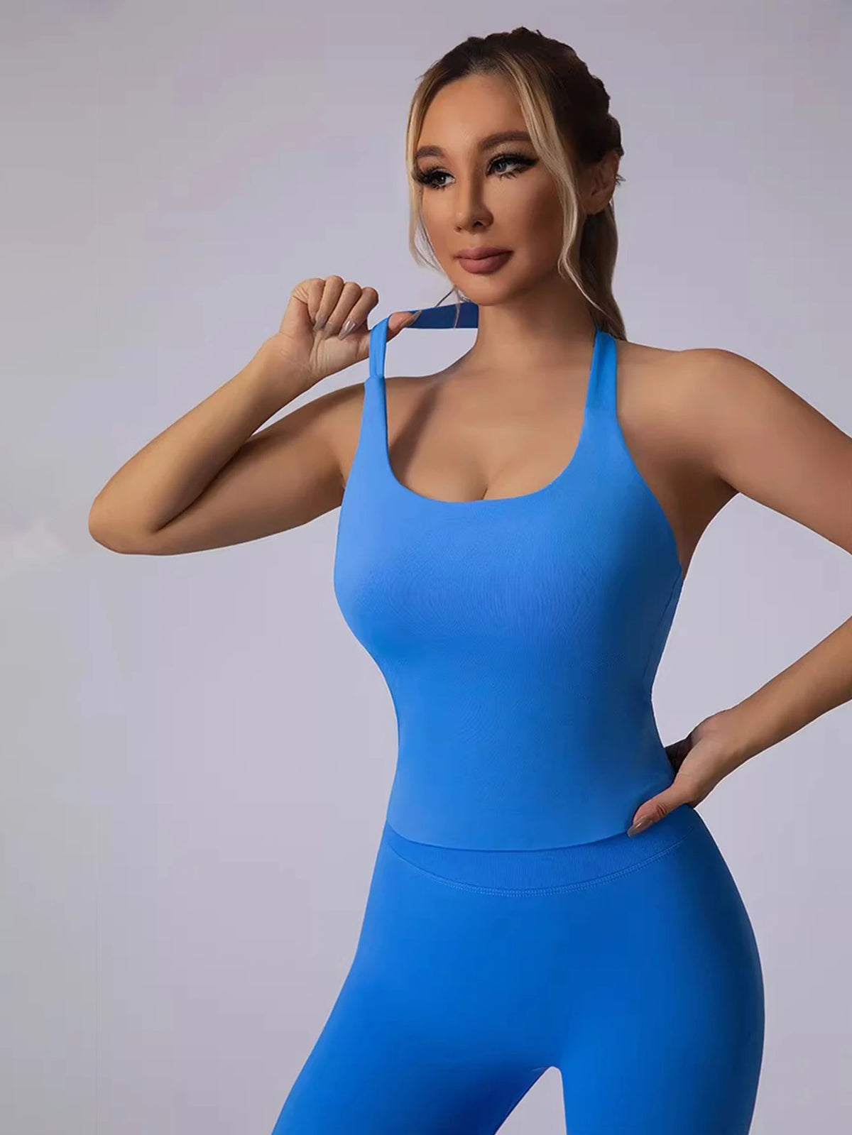 A woman models a bright blue seamless sports camisole set for yoga and fitness.