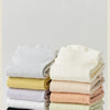 A stack of four pairs of non-slip yoga socks in various pastel colors including beige, yellow, pink, and mint.