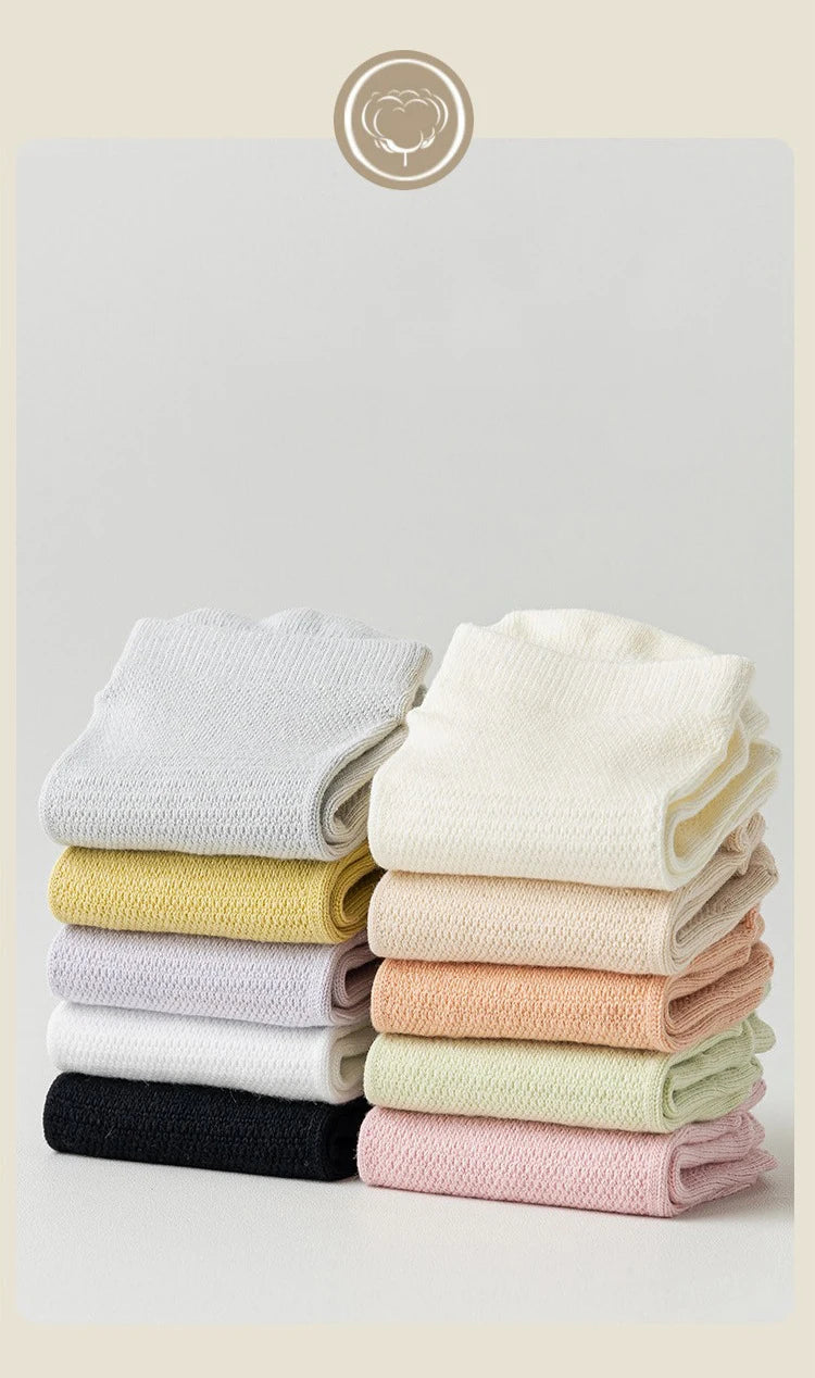 A stack of four pairs of non-slip yoga socks in various pastel colors including beige, yellow, pink, and mint.
