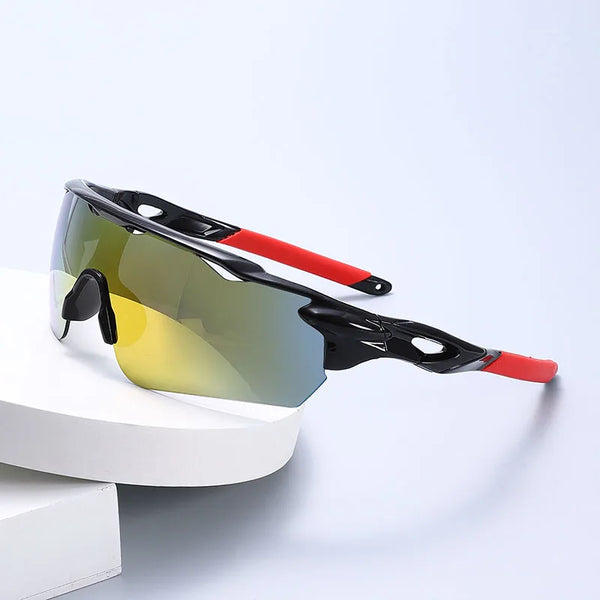 A pair of black sports sunglasses with yellow lenses and red accents resting on a white surface.