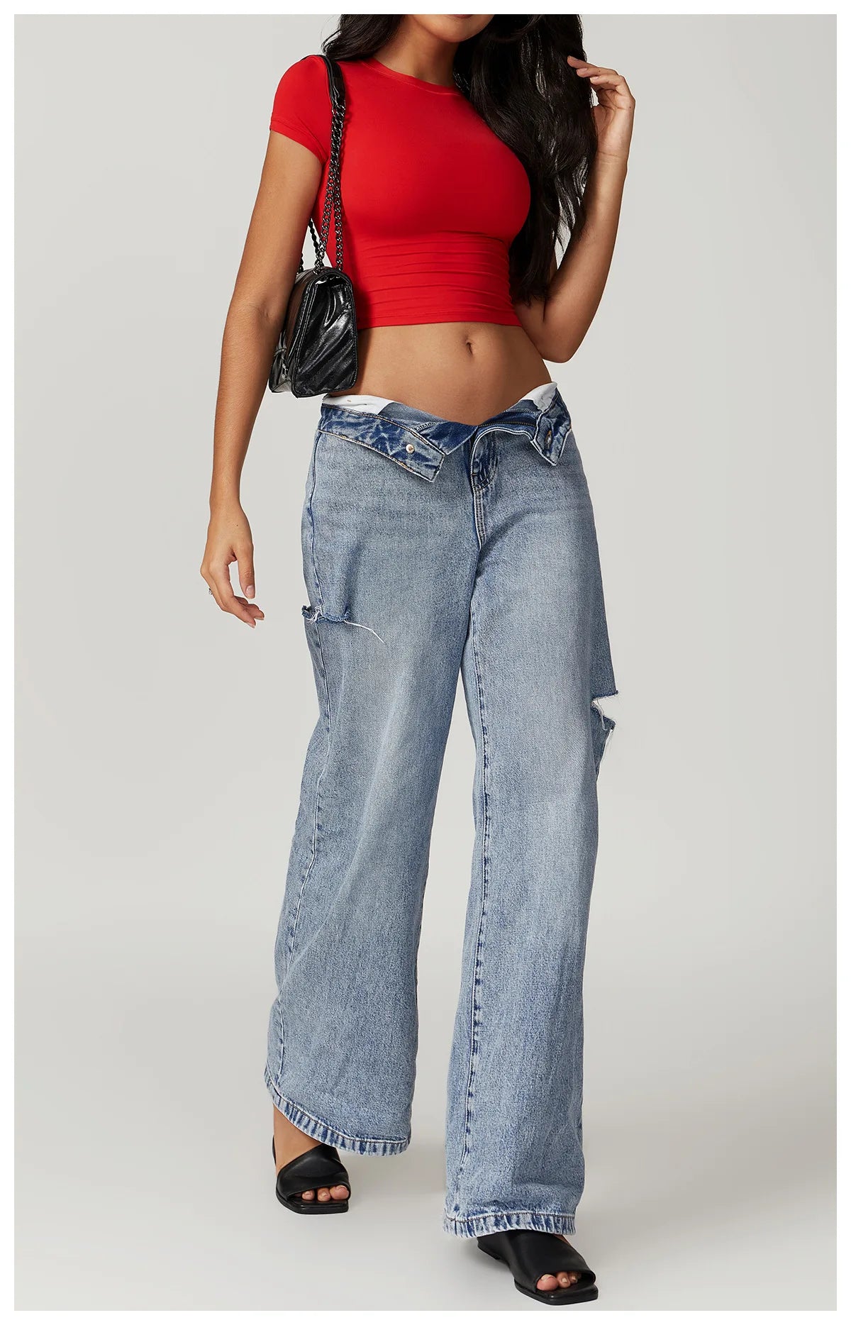 Una mujer vistiendo una camiseta deportiva de yoga y fitness roja y jeans azul claro.