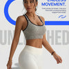 A woman models a seamless racerback sports bra and matching leggings in gray and white.
