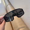 A pair of black UV400 cycling sunglasses is held against a light-colored surface.