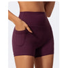 A model displays a pair of dark purple high-waist yoga and workout shorts.