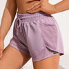 A model wears light purple athletic shorts with mesh pockets and a matching crop top.