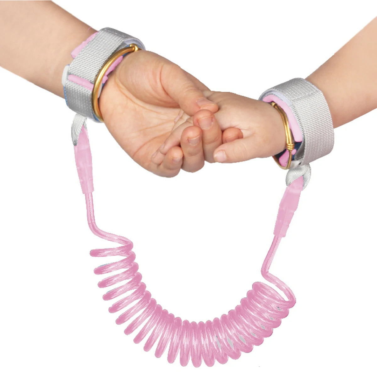 A pink adjustable child safety harness and leash is shown being held by a child's hands.