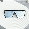 Pair of black-framed retro square sunglasses with reflective blue lenses resting on a white, wavy surface.