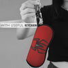 A hand holds a red spider web shaped keychain pouch with a metal keyring against a gray background.