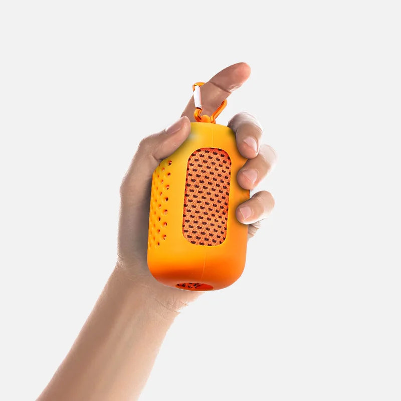 A hand is holding an orange cooling towel with a perforated texture and an orange strap.