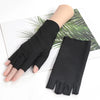 A hand wearing a black thin stretch elastane glove is shown against a background of green palm leaves.