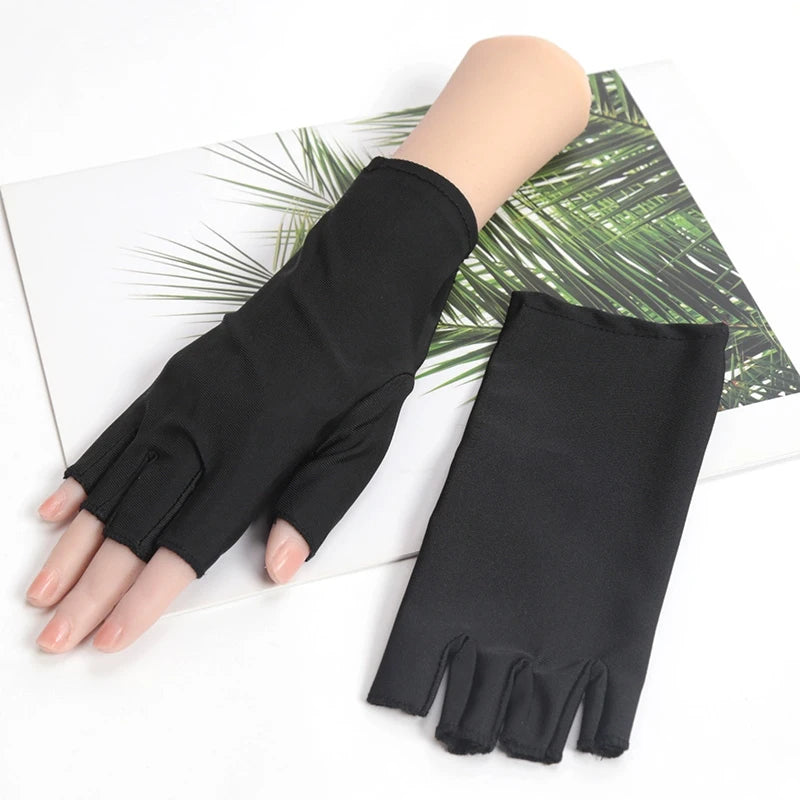 A hand wearing a black thin stretch elastane glove is shown against a background of green palm leaves.
