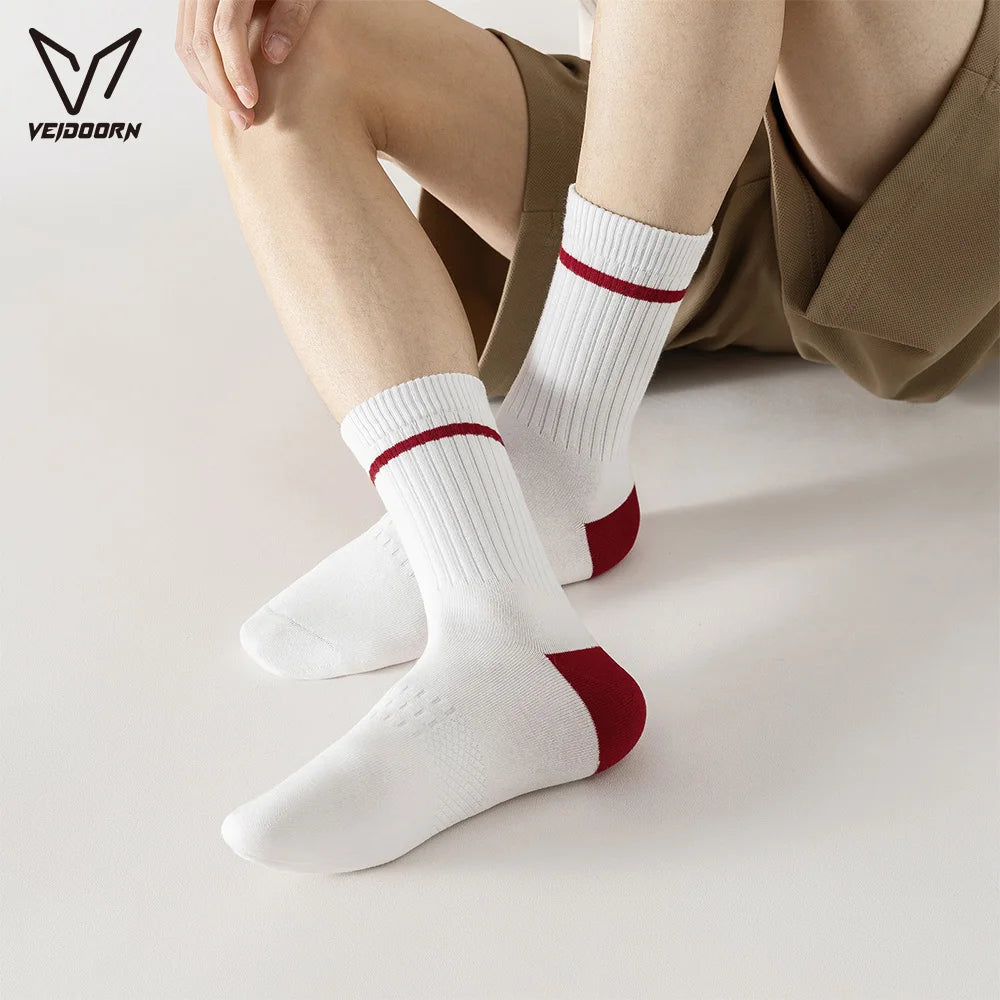 A person's leg wearing white crew socks with red stripes and a tan shirt, shown from the side.