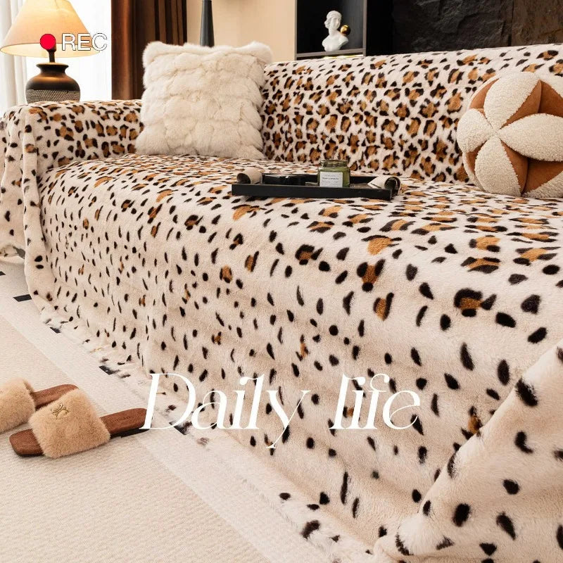A plush leopard print sofa cover blanket with cream and brown tones is displayed on a light floor.