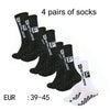 Four pairs of black and white men's athletic soccer socks with non-slip grip