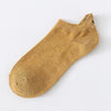 Un par de calcetines tobilleros amarillo mostaza con textura acanalada y detalles de cara sonriente bordados.