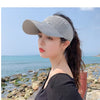 A woman wearing a gray breathable anti-UV adjustable sun hat outdoors near the sea.