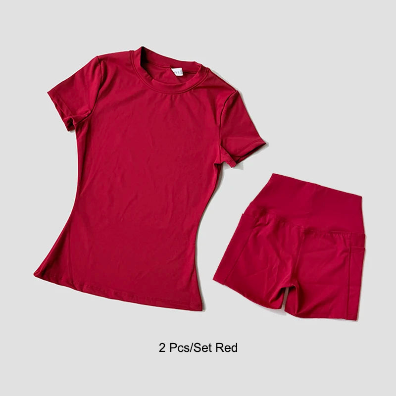 Un conjunto de ropa de yoga roja de talle alto para mujer, que incluye una blusa de manga corta y pantalones cortos a juego.