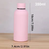 A pink double-layer vacuum thermos cup standing upright on a wooden surface.