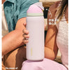 A person holds a pink insulated tumbler with a straw lid, demonstrating its use.