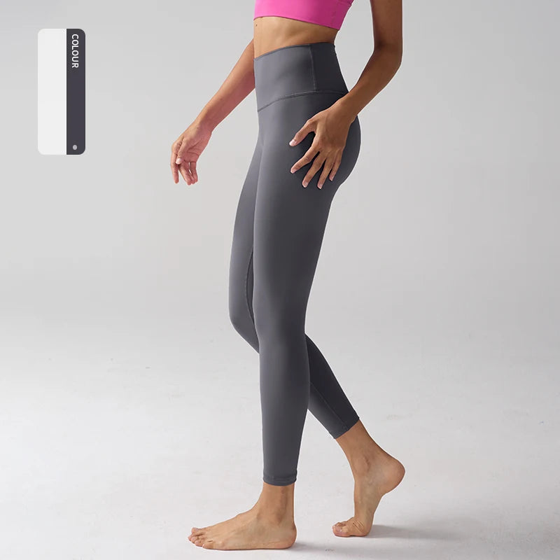 Un mannequin porte des leggings gris taille haute de sport et un haut rose, debout sur un fond clair.