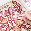 Una mano usa un pincel para aplicar pegatinas faciales rosas y amarillas sobre papel estampado.