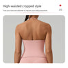 Eine Frau in einem pinken, hoch taillierten Crop-Top und passenden Unterteile, von hinten gezeigt.