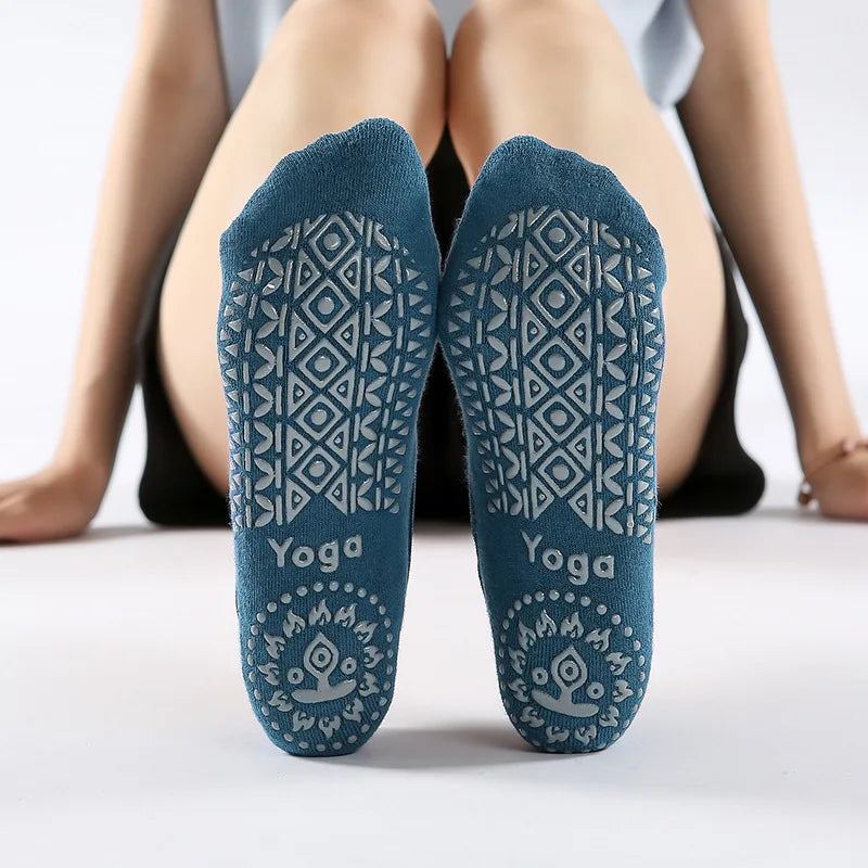 Pair of teal silicone yoga socks with a geometric pattern and the word Yoga printed on the heel