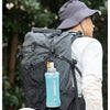 Mochila para llevar con botella de agua deportiva de silicona, demostrando uso portátil al aire libre.