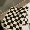A black and white checkered soft coral fleece face towel lying on a white surface.