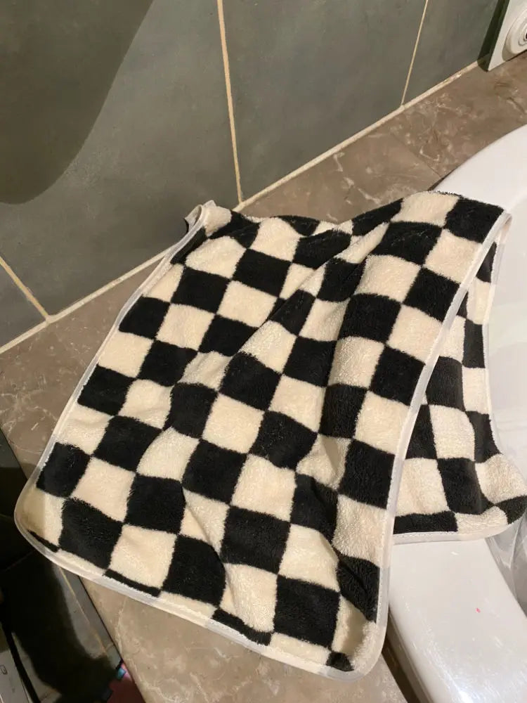 A black and white checkered soft coral fleece face towel lying on a white surface.