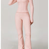 A woman wearing a seamless, long-sleeved pink yoga sports set consisting of a top and pants.
