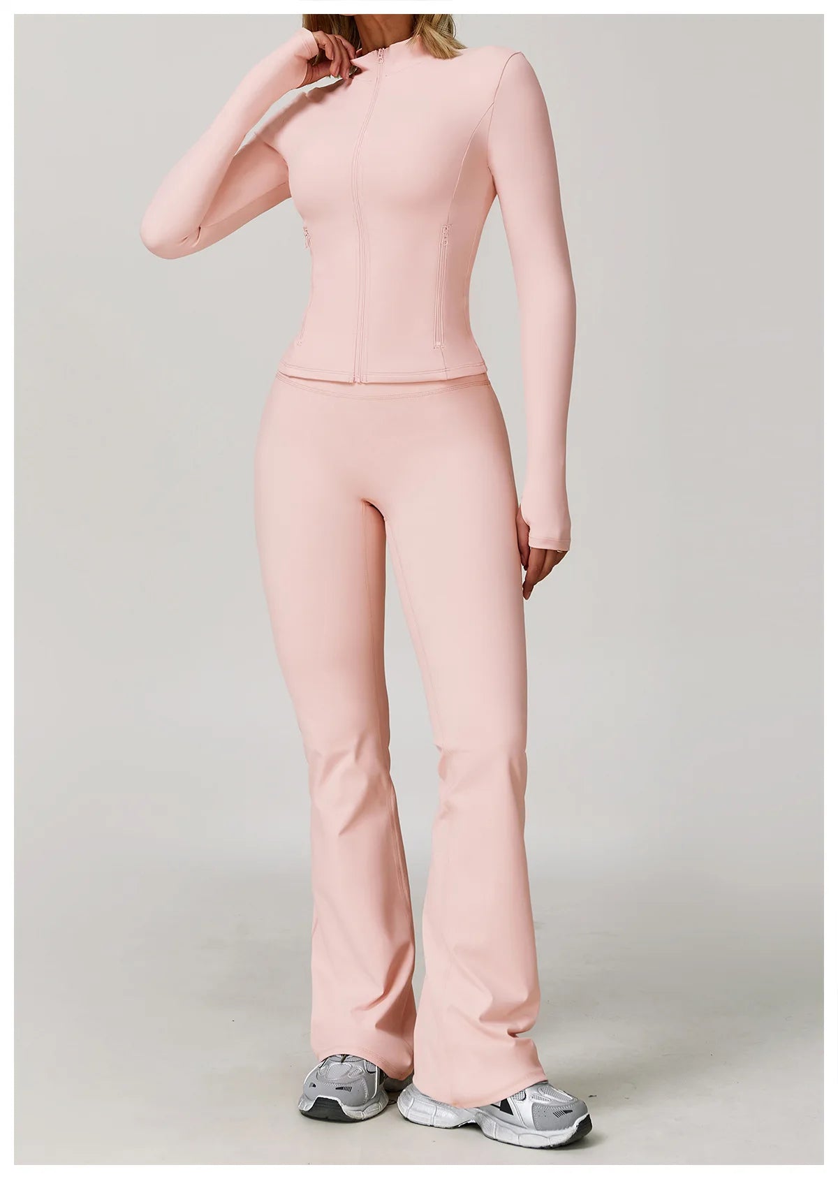 A woman wearing a seamless, long-sleeved pink yoga sports set consisting of a top and pants.