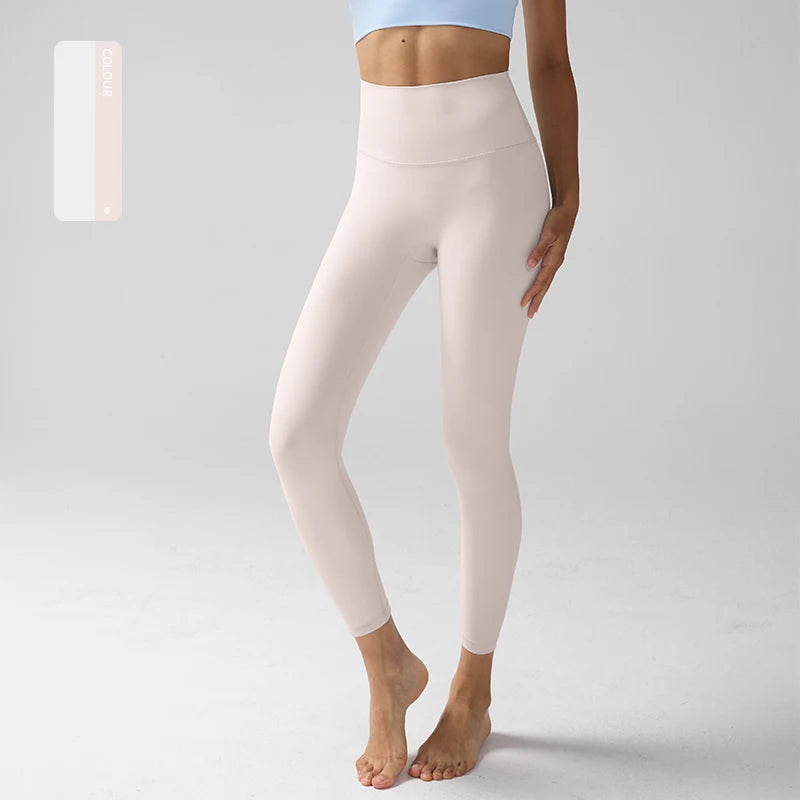 Un modèle porte des leggings de performance rose pâle à taille haute et un haut bleu.