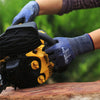 A hand wearing blue work gloves is operating a yellow power tool, with green foliage in the blurred background.