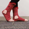 Pair of pink knitted crocodile animal socks worn on a person's foot.
