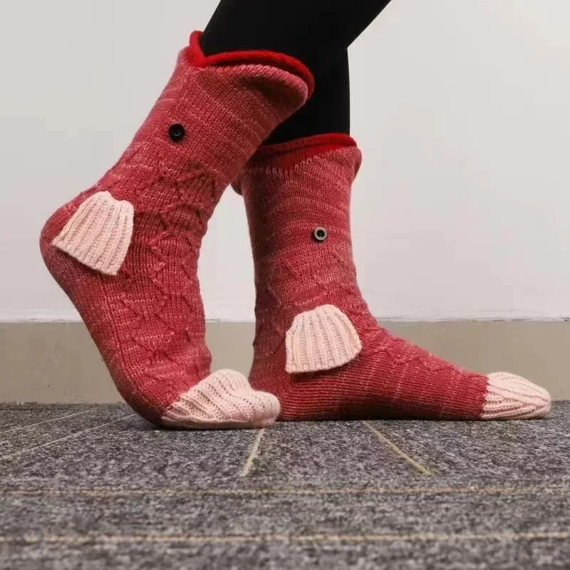 Pair of pink knitted crocodile animal socks worn on a person's foot.