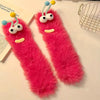 Pair of bright pink plush caterpillar floor socks with yellow and blue accents