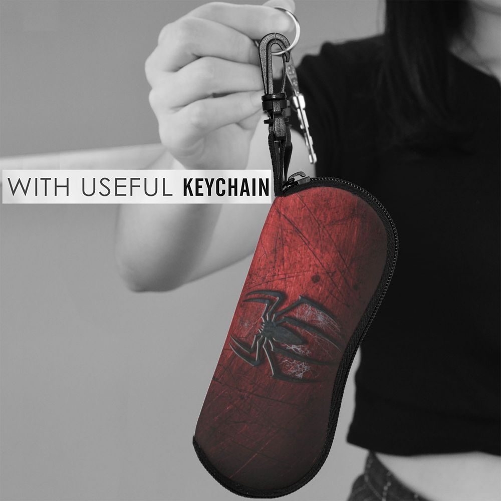A hand holds a leather pouch with a spider web design attached to a keychain.
