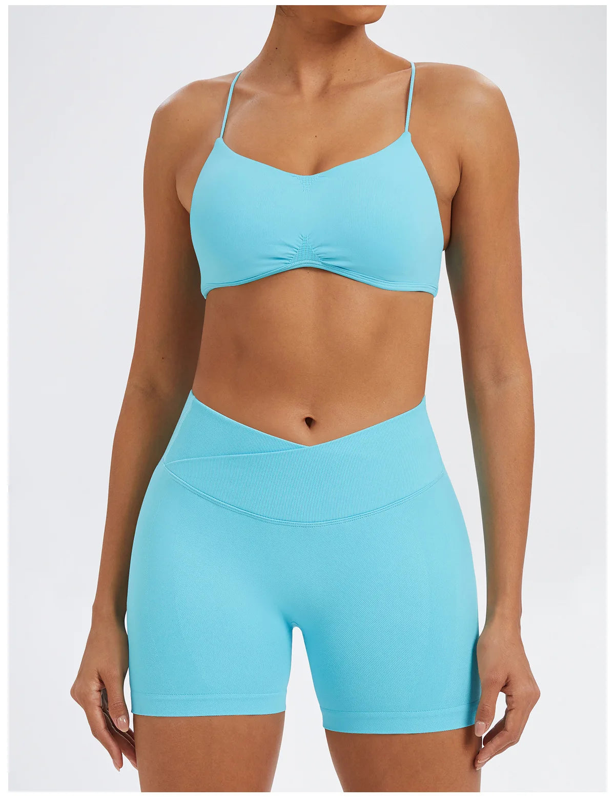 A model wearing a light blue seamless high-waist yoga set consisting of a cropped top and matching shorts.