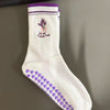 Weiße Strick-Yoga-Socken mit lila Zierrand und kleiner Blumenstickerei an der Zehe.
