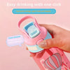 A hand is drinking from a pink cartoon straw sippy water bottle with a light blue silicone nipple.