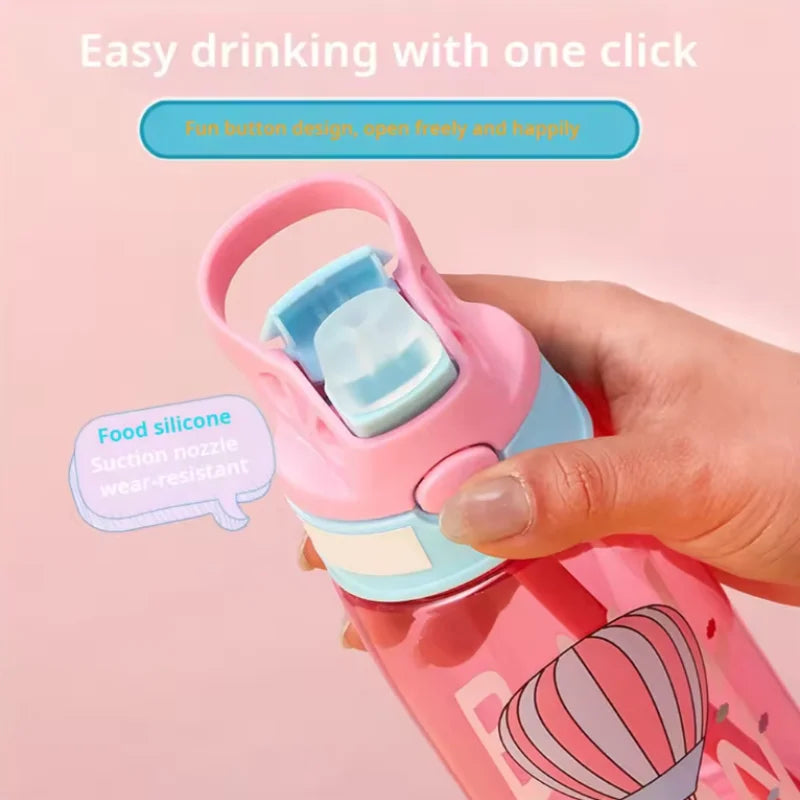 A hand is drinking from a pink cartoon straw sippy water bottle with a light blue silicone nipple.
