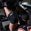 Black neoprene knee pads worn by a person during a lifting or fitness exercise.