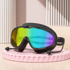Unos lentes de natación negros antiempañantes con lente arcoíris vibrante sobre una superficie rosa.
