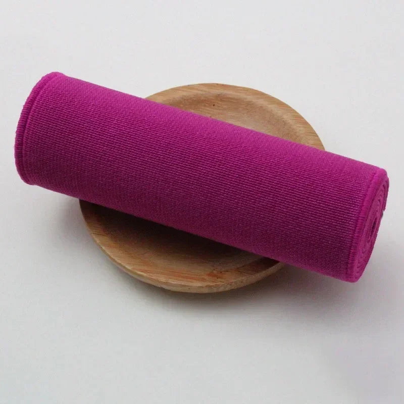 A vibrant magenta elastic band rolled up and resting on a wooden surface.